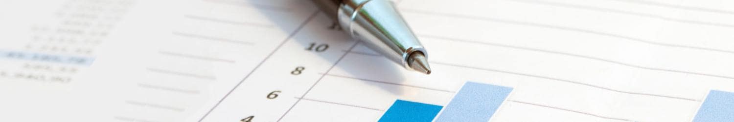 A pen rests on a document with blue bar charts and numerical data.