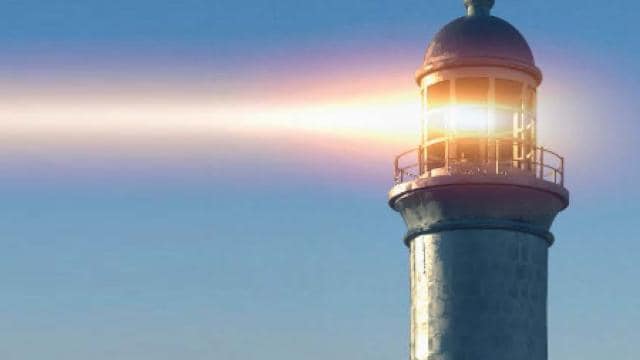 Ein Leuchtturm strahlt einen starken Lichtstrahl vor einem klaren blauen Himmel aus.