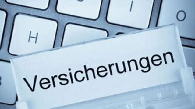 Nahaufnahme einer Tastatur mit einem Aktenreiter mit der Aufschrift „Versicherungen“.